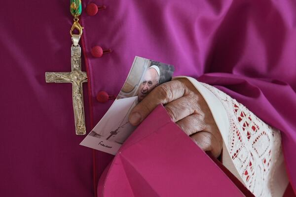 A prelate holds a picture of Pope Francis as he enters the atrium of St. Peter's Basilica at the Vatican, Wednesday, April 23, 2025, where the body of Pope Francis will lie in state for three days. (AP Photo/Andrew Medichini, Pool)