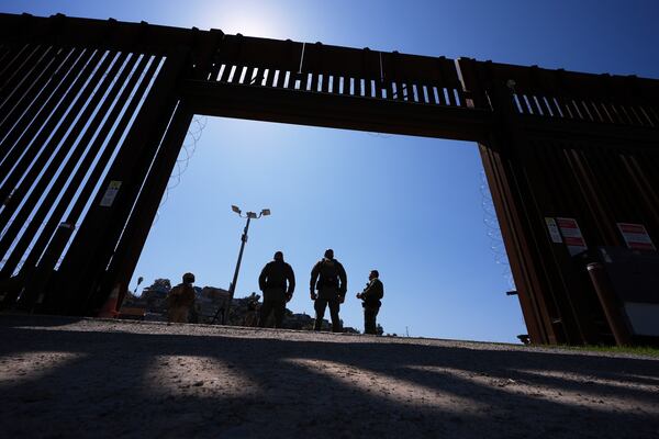 Border Patrol agents and members of the military stand inside a gate in one of two border walls separating Mexico from the United States during a news conference on joint operations involving the military and the Border Patrol, Friday, March 21, 2025, in San Diego. (AP Photo/Gregory Bull)