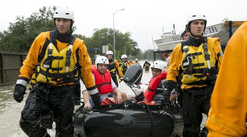 Rescuers remover Erik Peterson and his son Carlos, 10, from their home on Blackhaw Street in Houston on Tuesday.