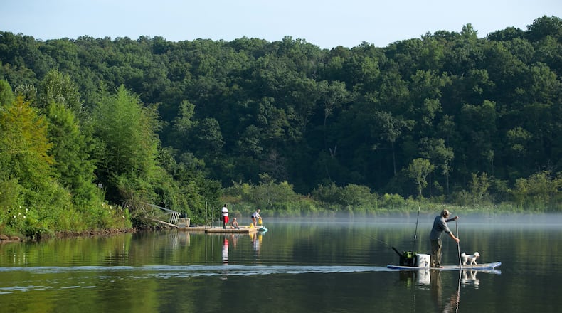 July 19, 2015 - Sandy Springs, Ga: People enjoy fishing off of the dock at Morgan Falls Overlook Park as a man paddles out on a paddle board with his dog on the Chattahoochee River Sunday, July 19, 2015, in Sandy Springs, Ga.