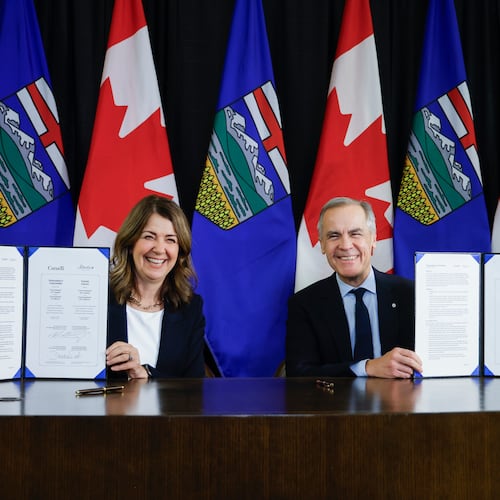 Prime Minister Mark Carney, right, signs an MOU with Alberta Premier Danielle Smith in Calgary, Alta., Thursday, Nov. 27, 2025. (Jeff McIntosh /The Canadian Press via AP)