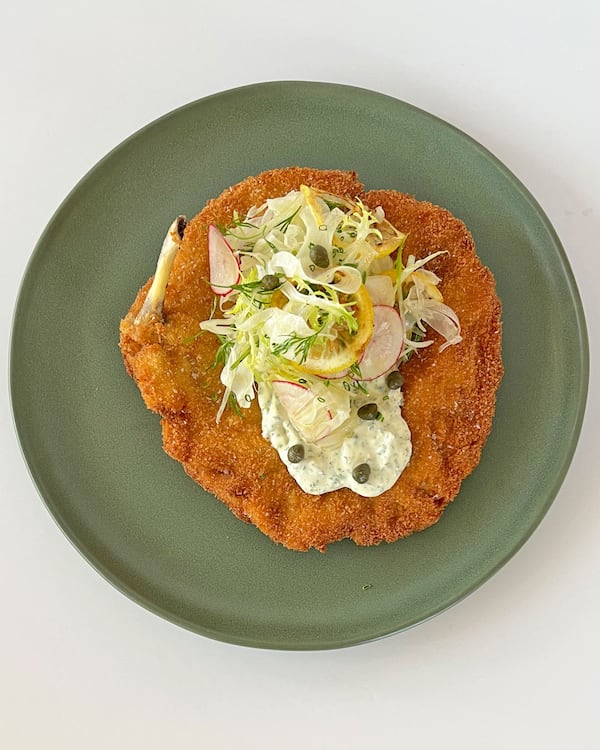 A green plate from Summerland Cafe holds a large piece of chicken schnitzel topped with minestrone and herb butter.