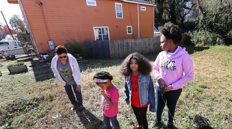 Rosario Hernandez (from left) and her granddaughters Ava Booker, 5, Aniyah Royal, 9, and Aryanna Maymi Booker, 11, look for pieces of slag on the vacant lot next to her home near Mercedes-Benz Stadium on Nov. 25, 2019, in Atlanta. Hernandez discovered slag, a byproduct of smelting, on the property. Her home has shown high levels of lead in the soil. CURTIS COMPTON / CCOMPTON@AJC.COM