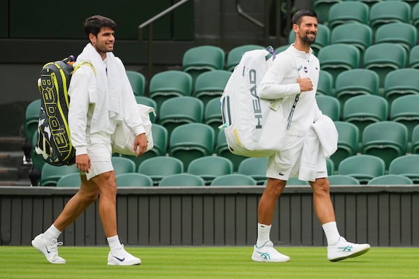 Novak Djokovic of Serbia, right, and Carlos Alcaraz of Spain, left, arrive for a practice session on Centre Court at the All England Lawn Tennis and Croquet Club, ahead of the Wimbledon Championships in London, Thursday, June 26, 2025. (AP Photo/Kirsty Wigglesworth)