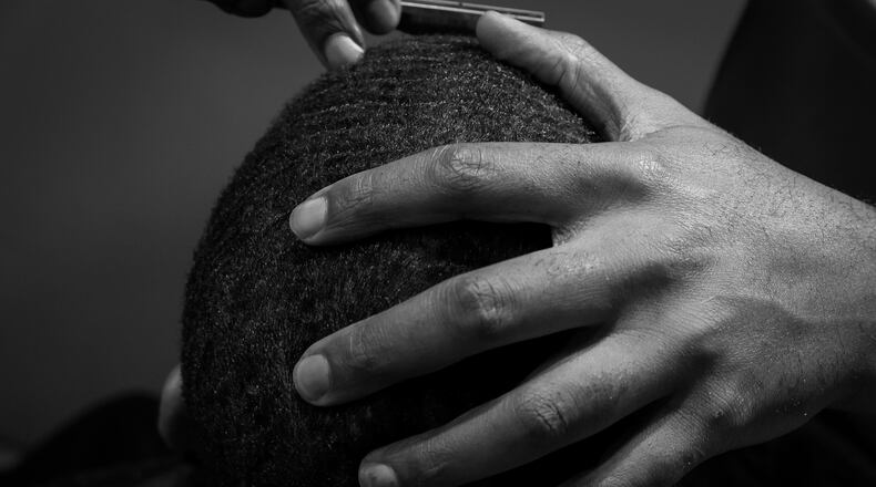 A man’s head is held in place by his barber, Donald Perry of Salon Ramsey in a photo by Antonio M. Johnson.
Courtesy of Antonio M. Johnson