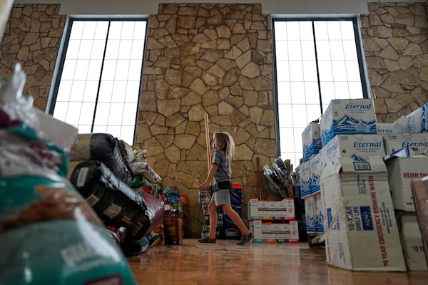 A child helps volunteers organize donations for victims of flash flooding in Texas inside the gym at Center Point Elementary in Center Point, Texas, Monday, July 7, 2025. (AP Photo/Ashley Landis)