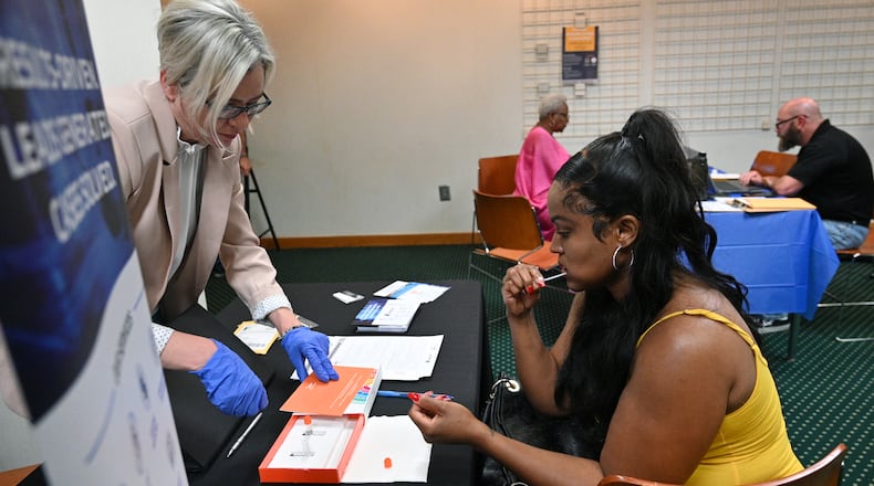 Chantel Martin, 34, of Columbia, South Carolina, uses a cotton swab to submit a DNA sample during a missing persons event and DNA drive at the DeKalb County Public Library. The county will host its third such event this weekend. (Hyosub Shin/AJC 2023)