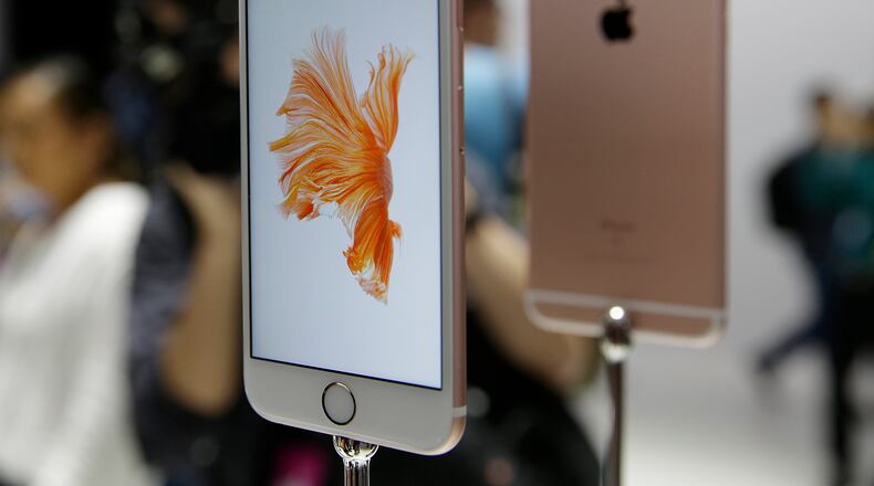 In this Sept. 9, 2015 photo, people look over the new Apple iPhone 6s models during a product display following an Apple event in San Francisco. Photography gets even better with Apple's new iPhones, making them worth getting for $100 more than last year's models.(AP Photo/Eric Risberg)