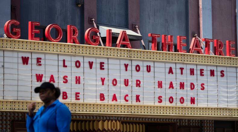 A woman walks past the Georgia Theatre in downtown Athens after the business closed amid coronavirus concerns. The city has been under a shelter-in-place order since March 19.