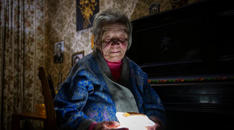 Raisa Derhachova holds a homemade flashlight during a power outage caused by regular Russian air strikes on the country's energy facilities in Kyiv, Ukraine, Tuesday, Jan. 13, 2026. (AP Photo/Dan Bashakov)