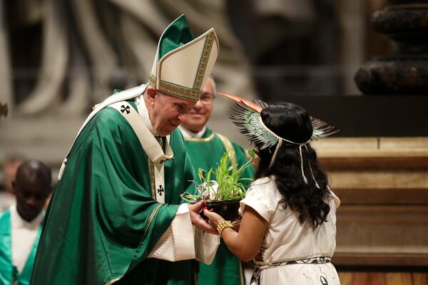 FILE - An Amazzonian indigenous girl gives Pope Francis a plant during the offertory of a Mass for the closing of Amazon synod in St. Peter's Basilica at the Vatican, Sunday, Oct. 27, 2019. (AP Photo/Alessandra Tarantino, file)