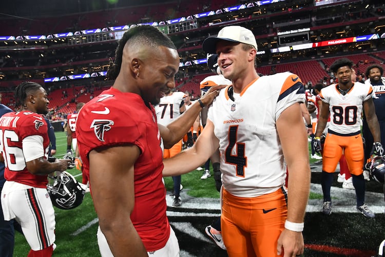 Falcons running back Bijan Robinson (left) and Broncos quarterback Sam Ehlinger greet each other after their preseason game at Mercedes-Benz Stadium on Friday, Aug. 14, 2026, in Atlanta. The Denver Broncos won, 27-7, over the Atlanta Falcons. (Hyosub Shin/AJC)