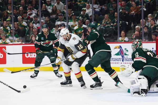 Vegas Golden Knights center Nicolas Roy (10) fights for the puck against Minnesota Wild defenseman Brock Faber (7) during the second period in Game 4 of an NHL hockey Stanley Cup first-round playoff series, Saturday, April 26, 2025, in St. Paul, Minn. (AP Photo/Stacy Bengs)