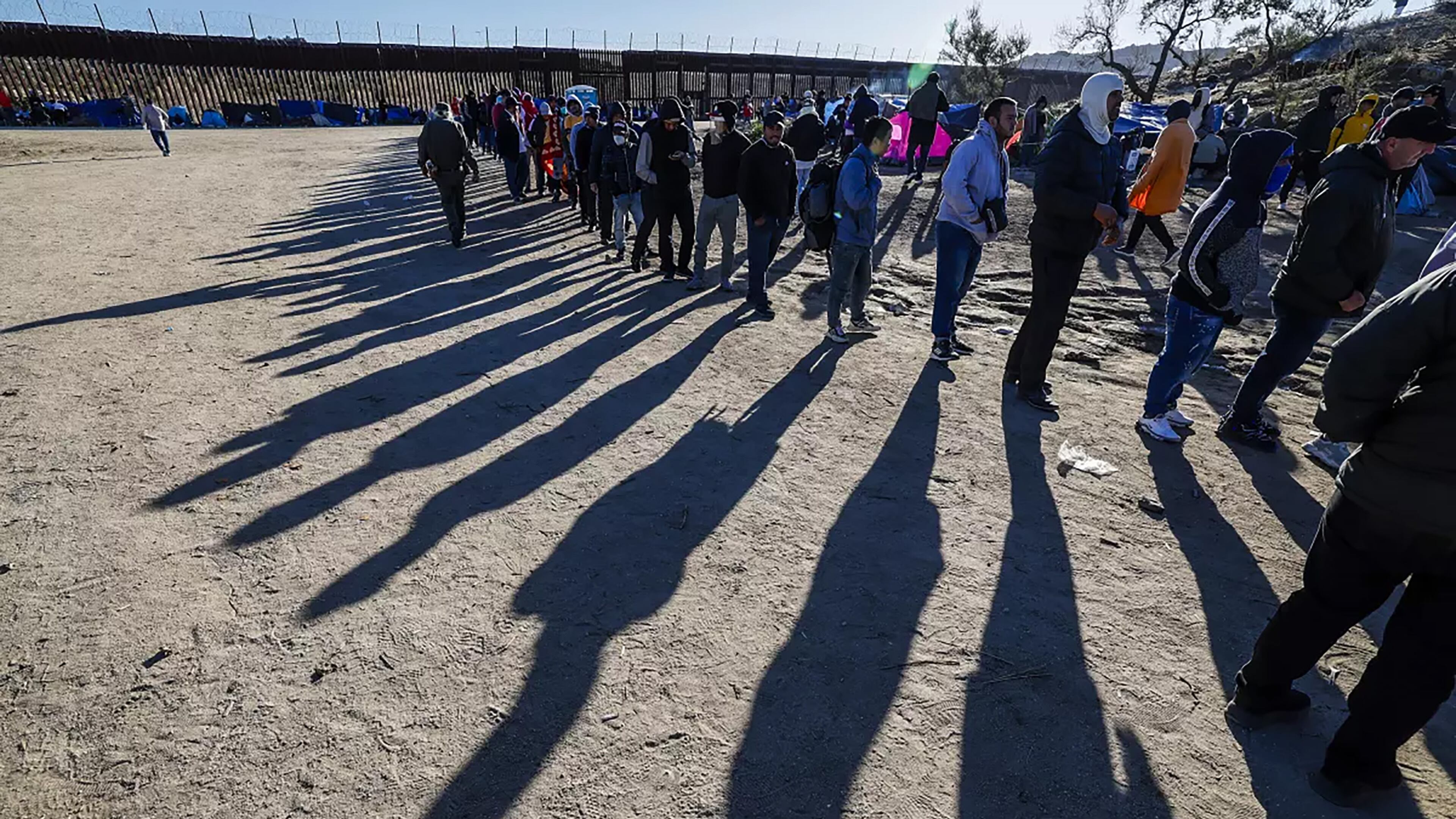 Migrants line up for food provided by volunteers at a makeshift camp near the border wall in Jacumba, California. (Robert Gauthier/Los Angeles Times/TNS)