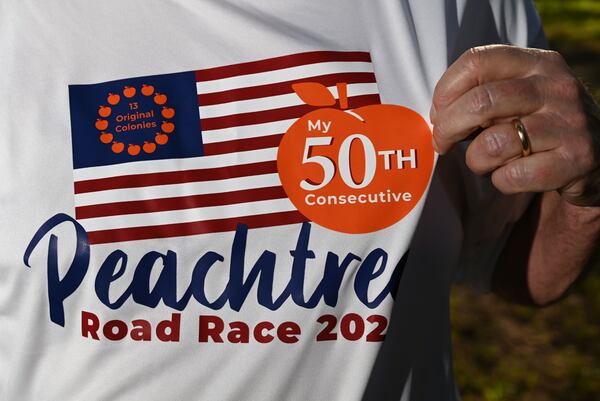 Greg Gates poses for a portrait wearing a custom-designed T-shirt to mark his 50th Peachtree Road Race. (Hyosub Shin/AJC)