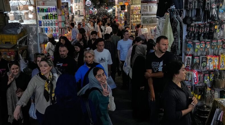 A woman flashes a victory sign while walking at Tehran's traditional main bazaar, Iran, Thursday, July 16, 2026. (AP Photo/Vahid Salemi)