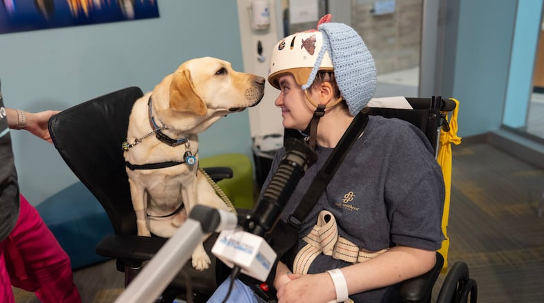 Cincinnati Children's Hospital facility dog Grover, left, looks to patient Kira Hodge at the hospital's Seacrest Studios as they produce a closed-circuit television show beamed into patient rooms, at Cincinnati Children's Hospital in Cincinnati, Monday, May 4, 2026. (AP Photo/Carolyn Kaster)