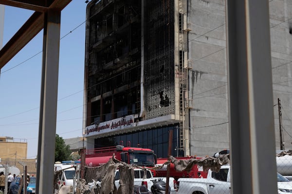 Firefighters gather in front of a burnt building in Kut, Iraq, Thursday, July 17, 2025 following a fire. (AP Photo/ Hadi Mizban)