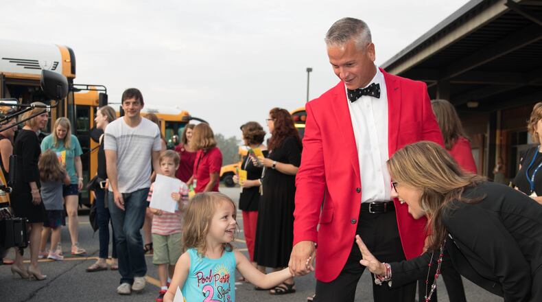 Pickett's Mill Elementary School Principal Dr. Benji Morrell, center, holds the hand of a student greeting a staff member during the Cobb School District's kindergarten ride along Wednesday. Credit: Cobb County School District.