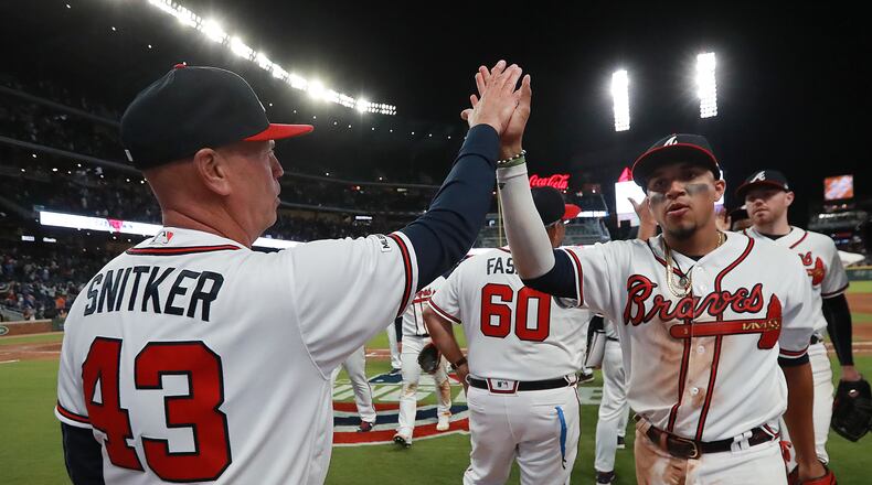 Braves' Johan Camargo (right) get five from manager Brian Snitker after beating the Chicago Cubs 6-4. Curtis Compton/ccompton@ajc.com