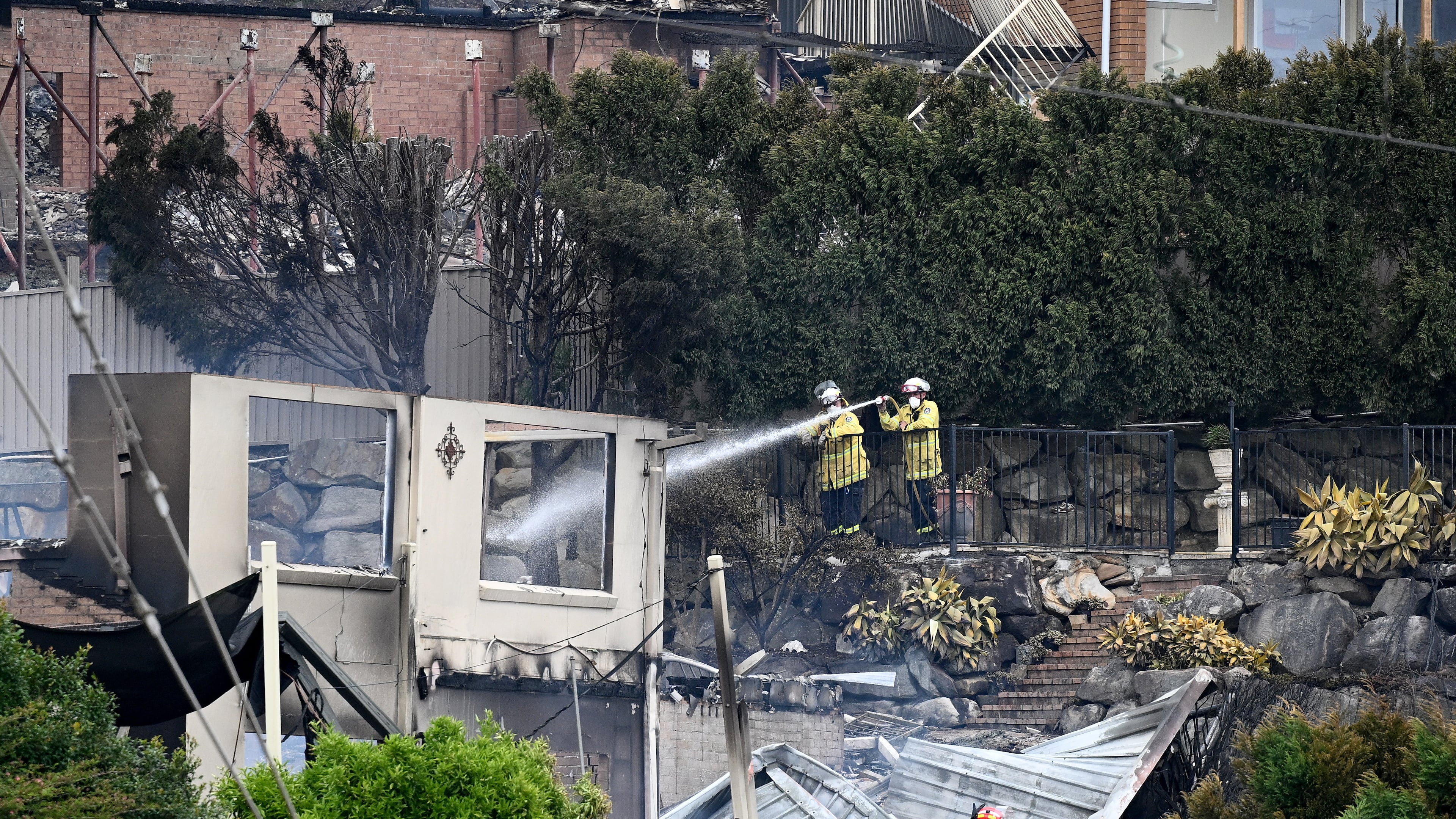 Firefighters ensure there are no flames left after a wildfire destroyed houses in Koolewong, Australia, Saturday, Dec. 6, 2025. (Dan Himbrechts/AAP Image via AP)