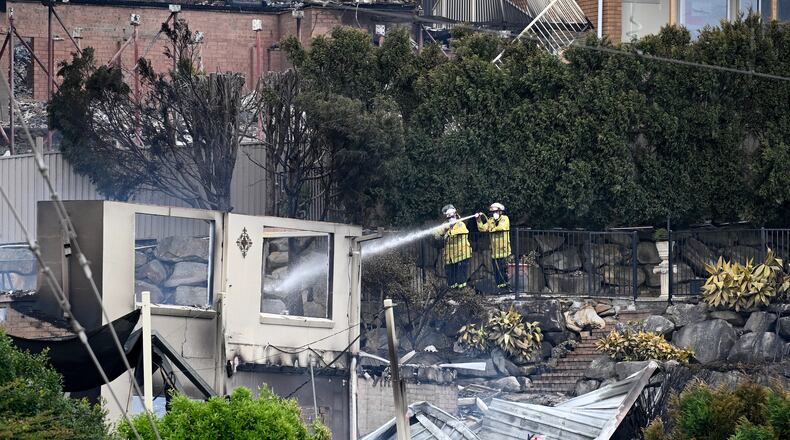 Firefighters ensure there are no flames left after a wildfire destroyed houses in Koolewong, Australia, Saturday, Dec. 6, 2025. (Dan Himbrechts/AAP Image via AP)