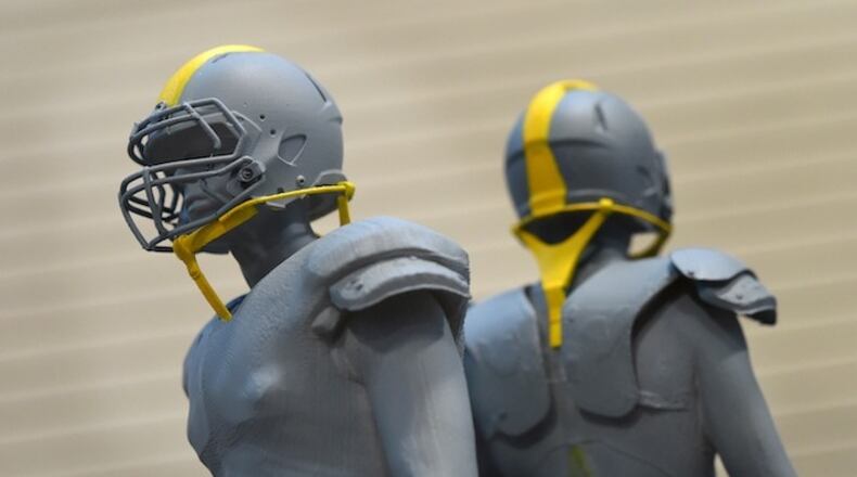 Two small models show how the safety straps might look on the helmet in Aberdeen, Md., on December 8, 2015. The U.S. Army Research Laboratory at Aberdeen Proving Ground is one of three groups working with Under Armour and the NFL to develop a safer football helmet, using straps to allow voluntary movement of the head but provide protection tension under hits. (Lloyd Fox/Baltimore Sun/TNS)