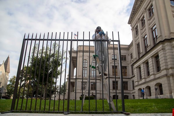 A Georgia Building Authority employee worked on a piece of tall fencing outside of the Georgia State Capitol in Atlanta on October 7, 2020. An 8-foot fence was part of a $5 million package that included security improvements at the Governor's Mansion and Department of Public Safety headquarters, according to Gov. Brian Kemp's office. (Alyssa Pointer/AJC)