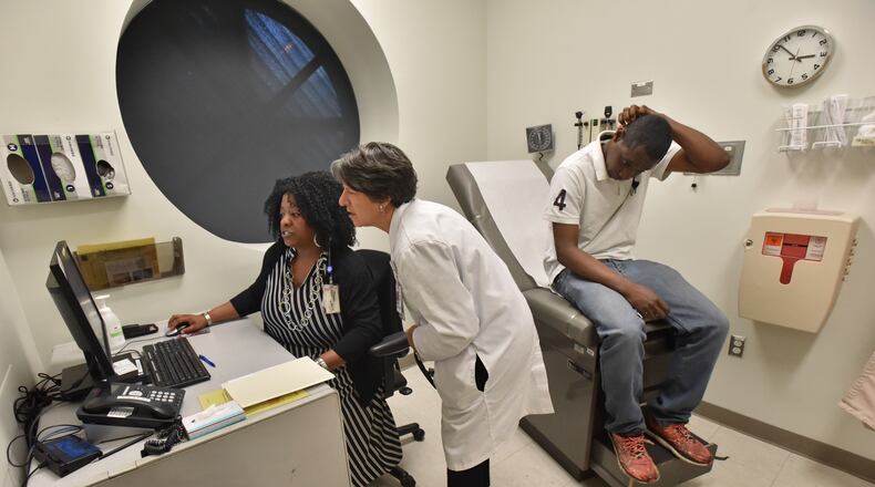 April 17, 2019 Atlanta - Karen Sutton (left), Licensed Clinical Social Worker (LCSW), and Dr. Claudia Vellozzi (center), medical director Chronic Care Clinic, confer as they look medical files of Alex Harris (right), who is a Chronic Care Clinic program participant, at Grady Memorial Hospital's Chronic Care Clinic in Atlanta on Wednesday, April 17, 2019. The Chronic Care Clinic is unique in that it's got not just a doctor and a nurse and assistants, but community health workers who get deeply involved in the patient's situation, a social worker who hooks them up with resources, a behavioral health clinician who addresses addiction and mental health issues, and a highly credentialed pharmacist. HYOSUB SHIN / HSHIN@AJC.COM