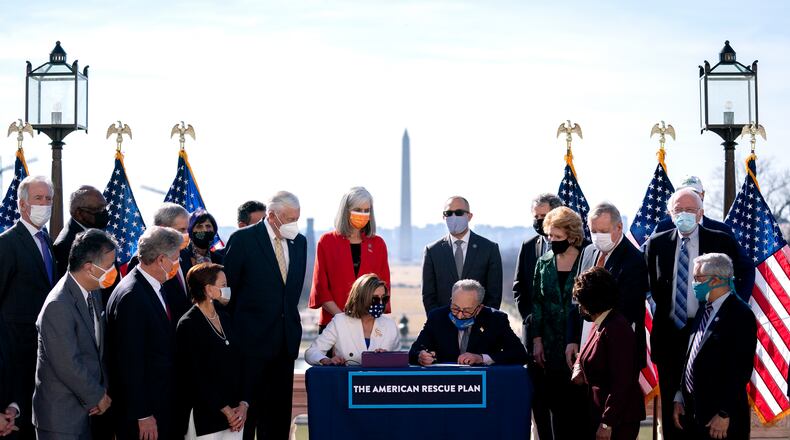 House Speaker Nancy Pelosi (D-Calif.), watches Senate Majority Leader Chuck Schumer (D-N.Y.), sign the COVID-19 relief bill during an enrollment ceremony outside the Capitol in Washington, with the Washington Monument in the background, on Wednesday, March 10, 2021. Congress gave final approval on Wednesday to President Joe Biden’s sweeping, nearly $1.9 trillion stimulus package, as Democrats acted over unified Republican opposition to push through an emergency pandemic aid plan that included a vast expansion of the country’s social safety net. (Stefani Reynolds/The New York Times)