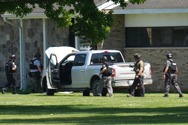 Police walk by an idle vehicle near CrossPointe Community Church in Wayne, Mich., Sunday, June 23, 2025. (AP Photo/Paul Sancya)