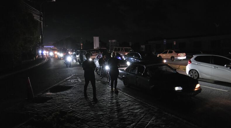 People watch as vehicles drive past during a blackout in Santo Domingo, Dominican Republic, Tuesday, Nov. 11, 2025. (AP Photo/Ricardo Hernandez)