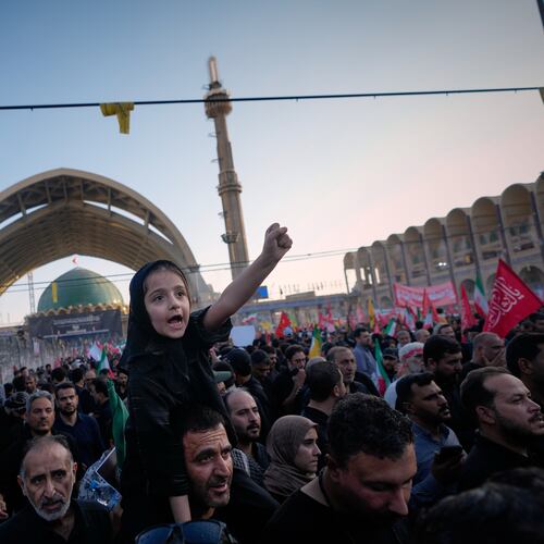 A little girl raises her fist from atop a man's shoulders as mourners gather during funeral ceremonies for slain Iranian Supreme Leader Ayatollah Ali Khamenei and members of his family at the Imam Khomeini Mosalla Grand Mosque in Tehran, Iran, Sunday, July 5, 2026. (AP Photo/Altaf Qadri)