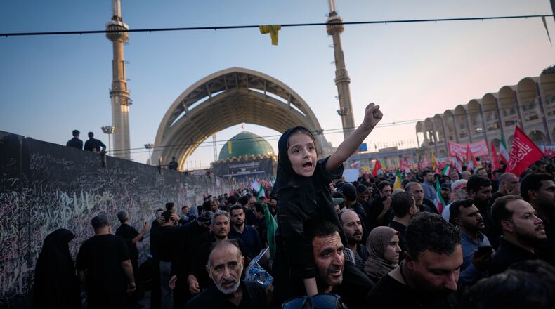 A little girl raises her fist from atop a man's shoulders as mourners gather during funeral ceremonies for slain Iranian Supreme Leader Ayatollah Ali Khamenei and members of his family at the Imam Khomeini Mosalla Grand Mosque in Tehran, Iran, Sunday, July 5, 2026. (AP Photo/Altaf Qadri)