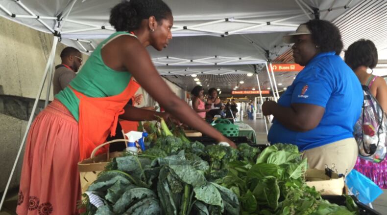 Cicely Garrett (left) helps Banesha Campbell purchase fresh produce at the MARTA Fresh Market on Friday, July 10, 2015 at MARTA's West End station.