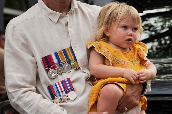 A father holds his child as during the Anzac Day commemorations in Nelson Bay, Australia, Friday, April 25, 2025. (AP Photo/Mark Baker)