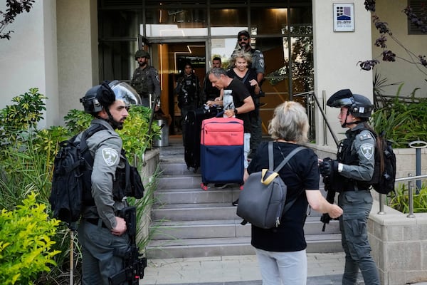 Israeli border police officers help residents to evacuate from a building damaged in an Iranian missile strike in Tel Aviv, Israel, Sunday, June 22, 2025. (AP Photo/Bernat Armangue)