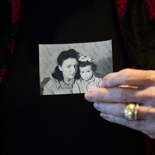 Holocaust survivor Ilana Shalem-Kantorowics born in the Nazi Bergen-Belsen concentration camp holds a photo of her with her mother Lola in the camp in 1946, in Tel Aviv, Israel, Jan. 26, 2026. (AP Photo/Ariel Schalit)