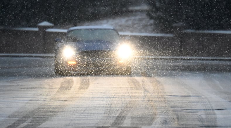 A car travels on a snow-covered road near the Mercer University campus in Macon. Snow began falling in Atlanta and across Middle and South Georgia on Tuesday afternoon and quickly started accumulating in some areas.