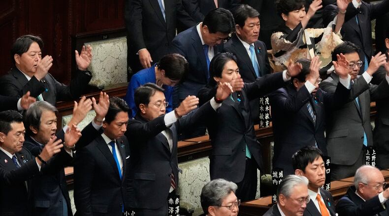 Japanese Prime Minister Sanae Takaichi, center in blue jacket, bows and other lawmakers cheer after dissolving the lower house, during an extraordinary Diet session at the lower house of parliament Friday, Jan. 23, 2026, in Tokyo. (AP Photo/Eugene Hoshiko)