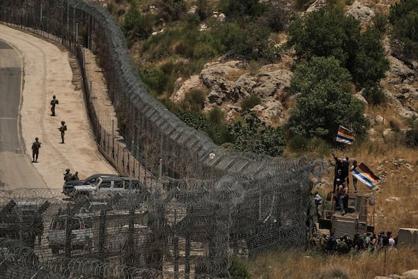 Israeli soldiers stand guard as Syrian Druze protest near the Israeli-Syrian border, as seen from the town of Majdal Shams in the Israeli-controlled Golan Heights, Wednesday, July 16, 2025, amid ongoing clashes between Syrian government forces and Druze armed groups in the southern Syrian city of Sweida. (AP Photo/Leo Correa)