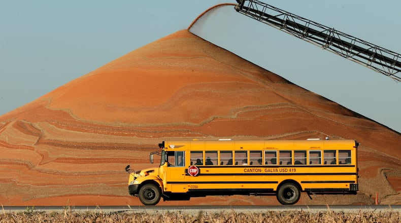 FILE - A school bus passes a pile of milo at a grain storage facility near Canton, Kan., Nov. 10, 2015. (AP Photo/Charlie Riedel, File)