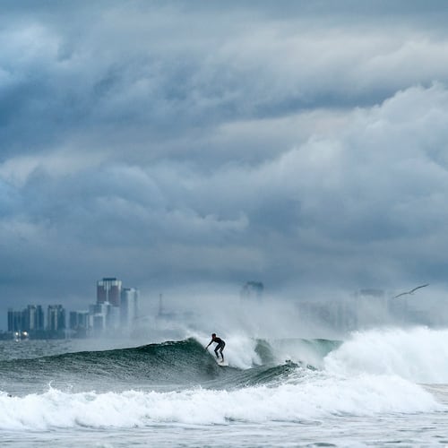 A surfer rides a wave as clouds gather above Bolsa Chica State Beach in Orange County, Calif., on Saturday, Nov. 15, 2025. (AP Photo/Noah Berger)