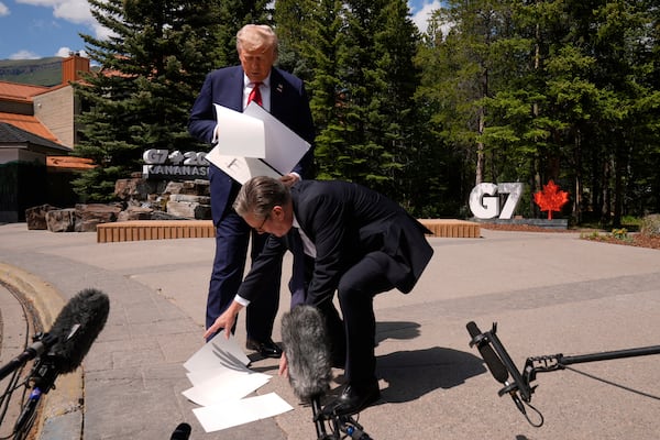 President Donald Trump drops papers as he meets with Britain's Prime Minister Keir Starmer on the sidelines of the G7 Summit, Monday, June 16, 2025, in Kananaskis, Canada. (AP Photo/Mark Schiefelbein)