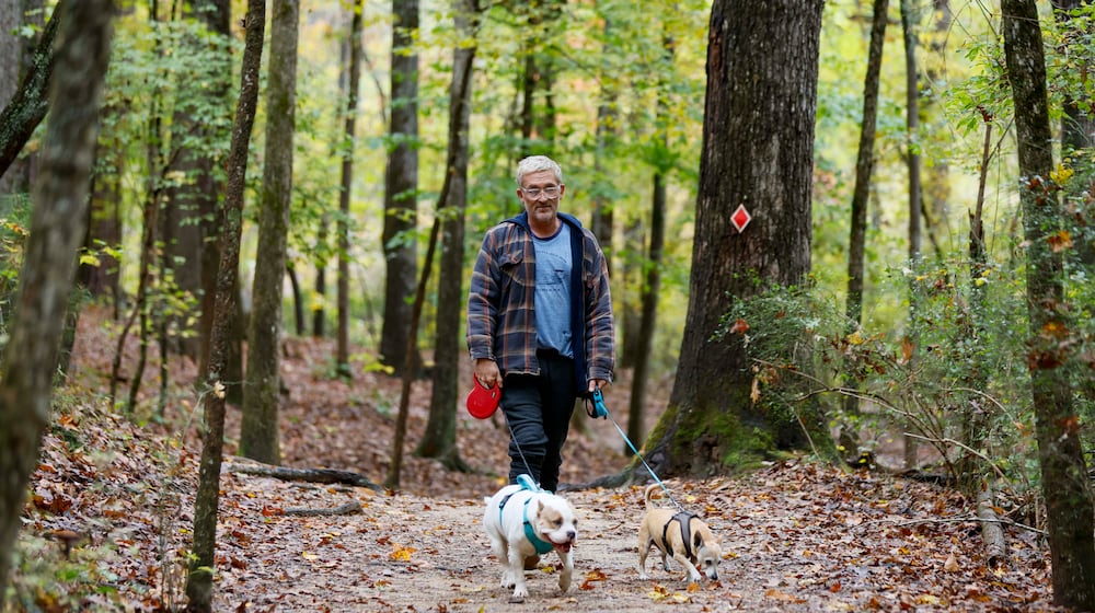 Terrance Wahl of Decatur takes a walk with his pets, Teddy and Tippi, along Sweet Water Creek in October 2025. (Miguel Martinez/AJC)