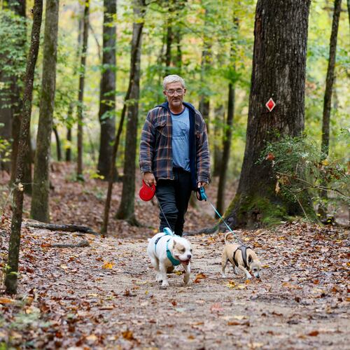 Terrance Wahl of Decatur takes a walk with his pets, Teddy and Tippi, along Sweet Water Creek in October 2025. (Miguel Martinez/AJC)