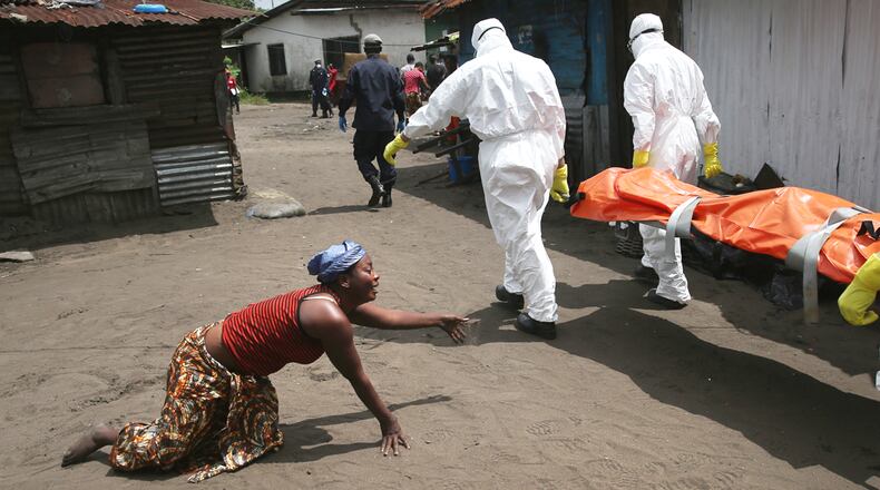 A woman crawls towards the body of her sister as Ebola burial team members take her sister Mekie Nagbe, 28, for cremation on Oct. 10, 2014 in Monrovia, Liberia.