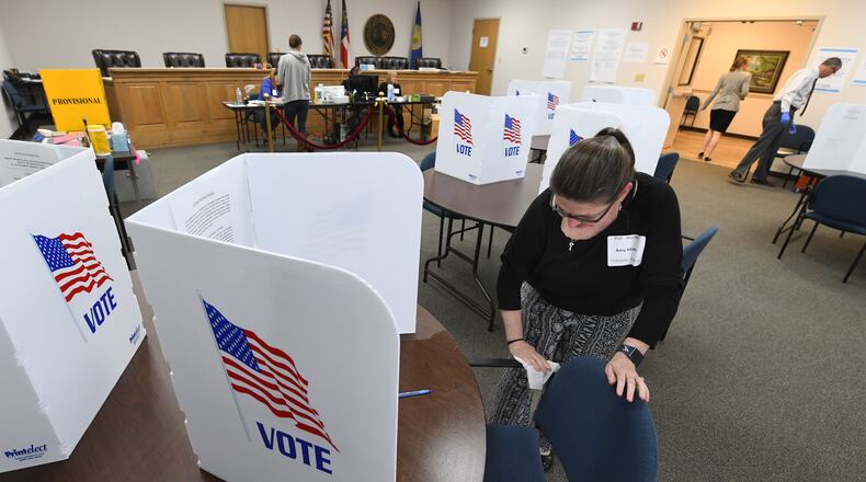Poll worker Amy Morris wipes down an area used by a voter during special election voting at city hall to fill an empty city council seat on Tuesday, March 24, 2020, in Dacula. The voting happens to on a day that was supposed to be the test run for the state’s new election system before coronavirus COVID-19 caused it to be called off. The city uses paper ballots and doesnt forsee switching to the new sytem because the machines are not given to municipalities for special elections.