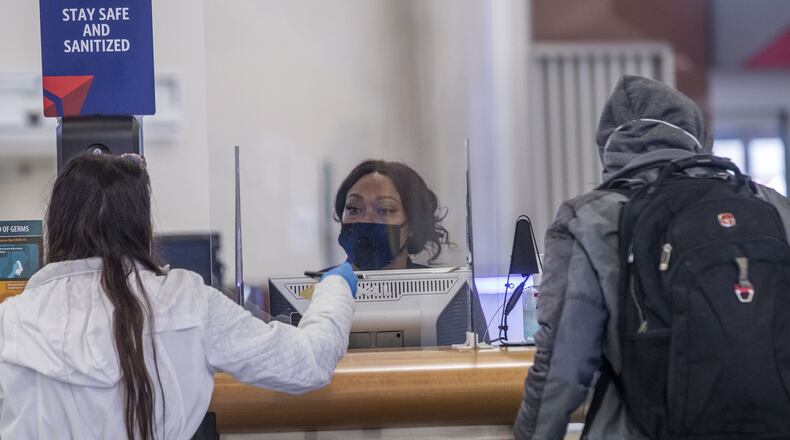 A Delta employee works behind plexiglass screens as she checks-in passengers in the domestic terminal at Hartsfield-Jackson. (ALYSSA POINTER / ALYSSA.POINTER@AJC.COM)