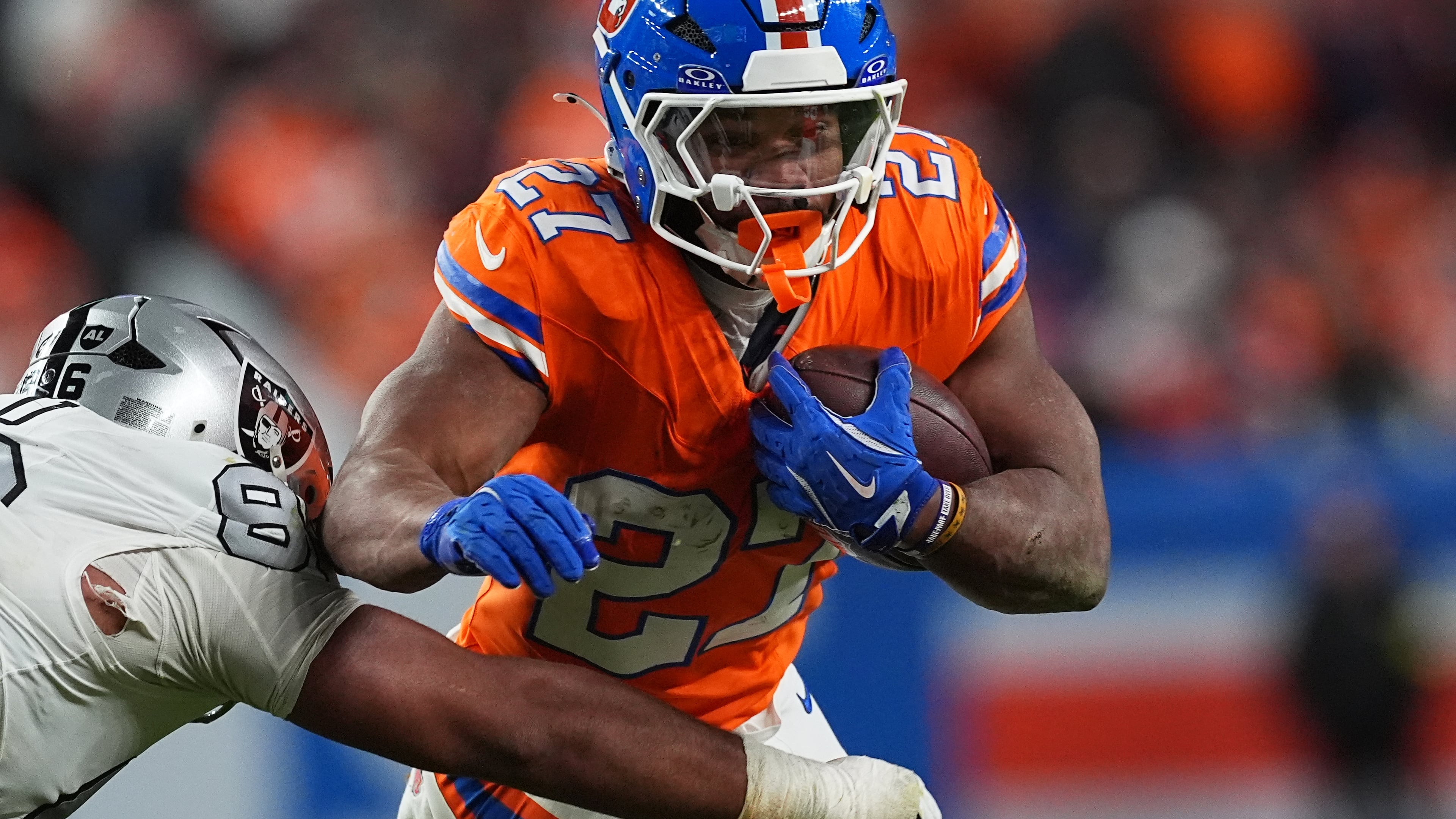 Denver Broncos running back J.K. Dobbins, right, runs for a first-down as Las Vegas Raiders defensive tackle Jonah Laulu makes the stop in the second half of after an NFL football game Thursday, Nov. 6, 2025, in Denver. (AP Photo/David Zalubowski)